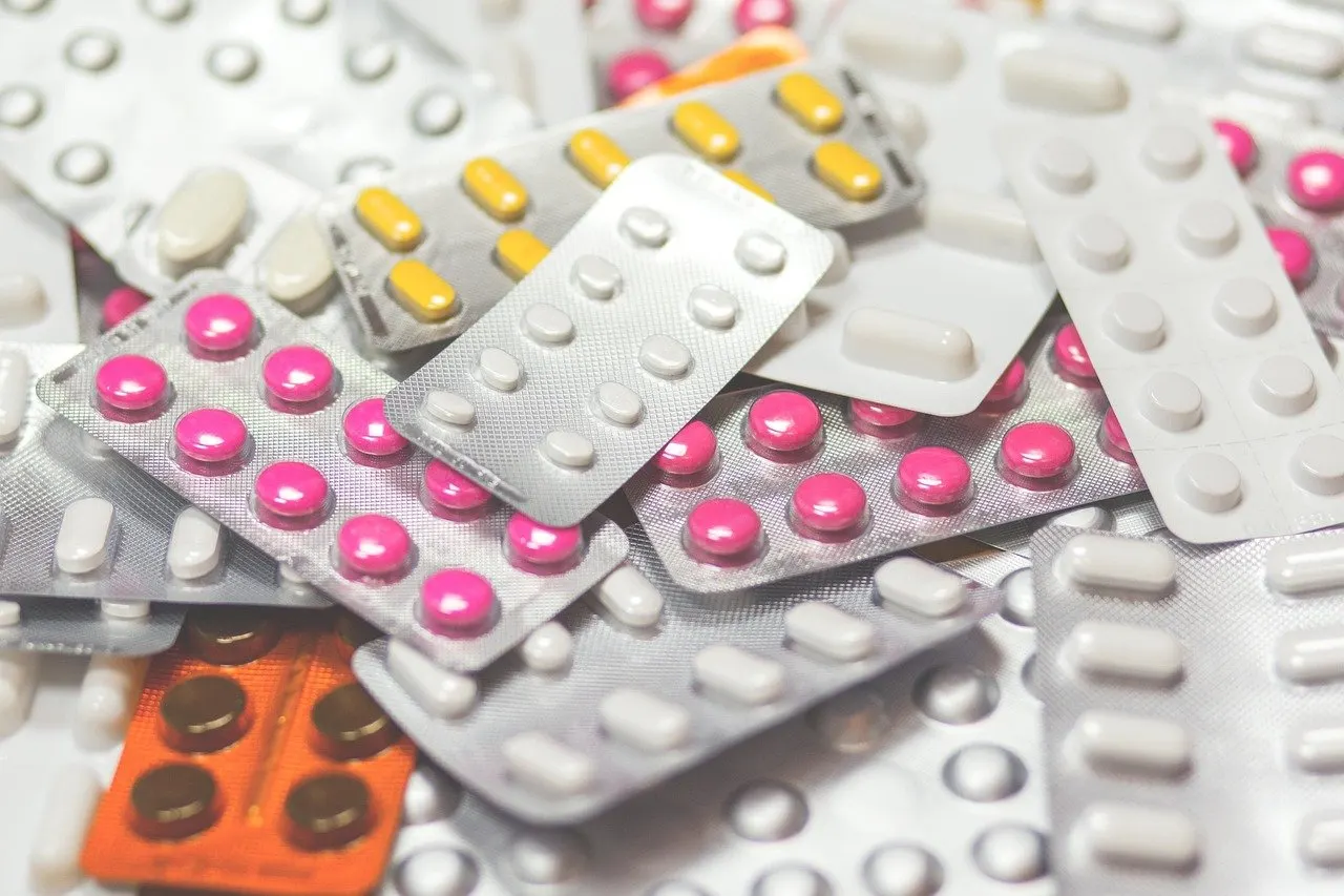 Viele Blisterpackungen mit weißen, rosa und gelben Tabletten, dazwischen eine orangefarbene Packung, liegen durcheinander auf einem Haufen
